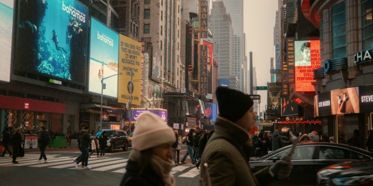 People walk in times square on a cloudy day.