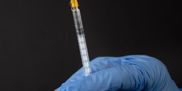 person in white pants and white shirt holding clear glass tube