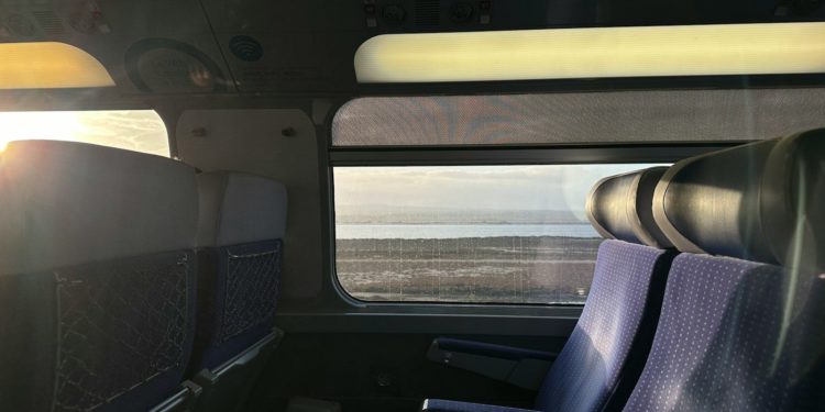 the inside of a train with a view of the ocean