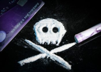 A skull and crossbones shape made of white powder on a black surface