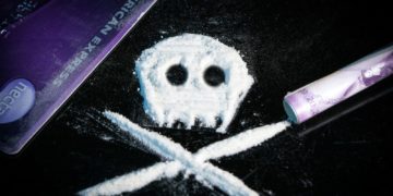 A skull and crossbones shape made of white powder on a black surface
